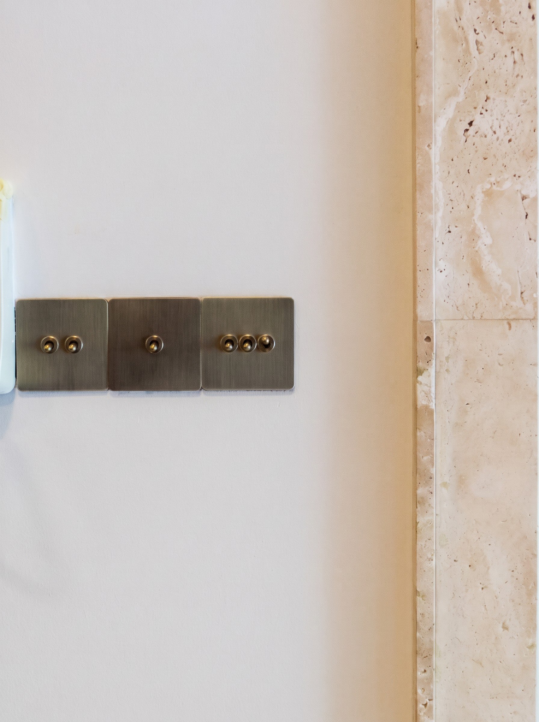 Hampton Residences brass switches beside travertine detailing