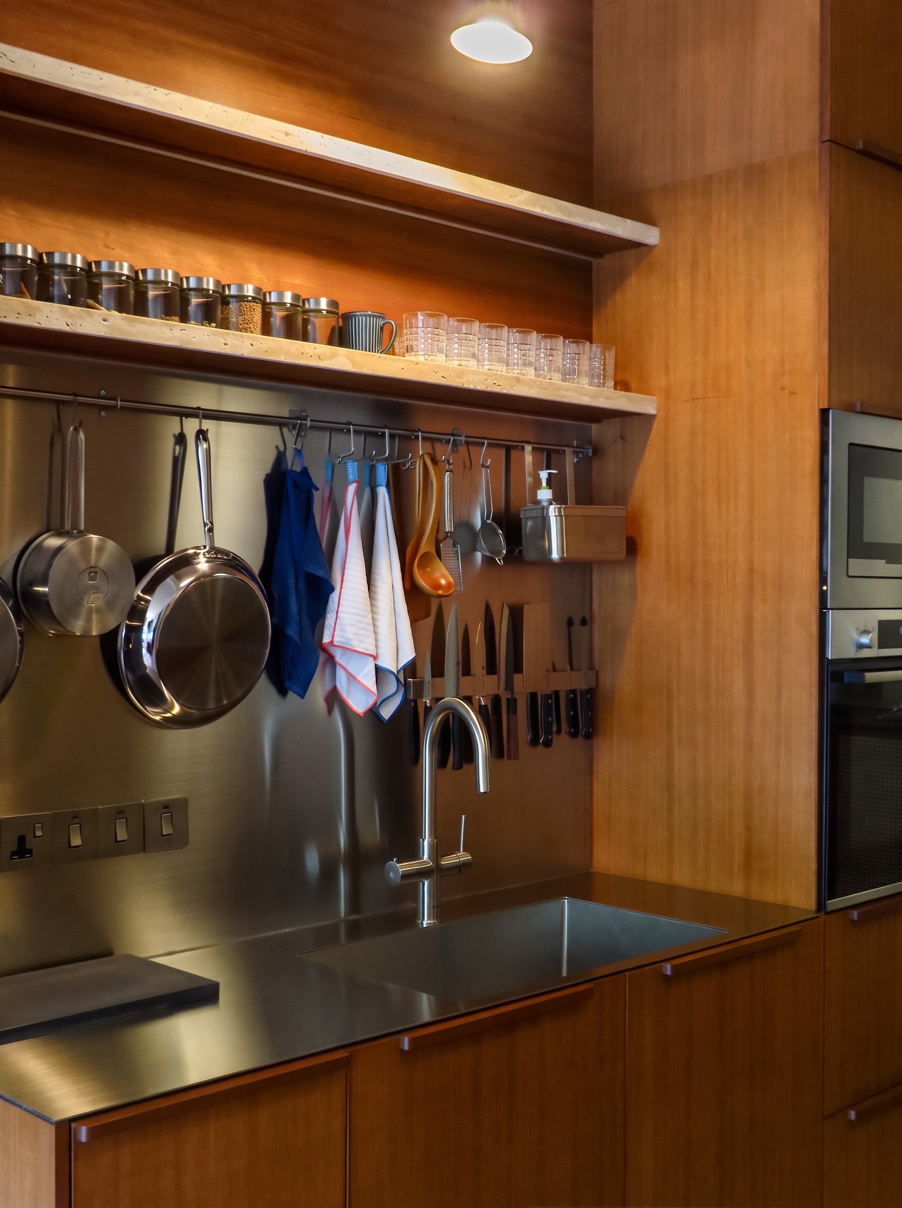 Hampton Residences stainless-steel sink and backsplash with timber cabinetry and travertine shelves