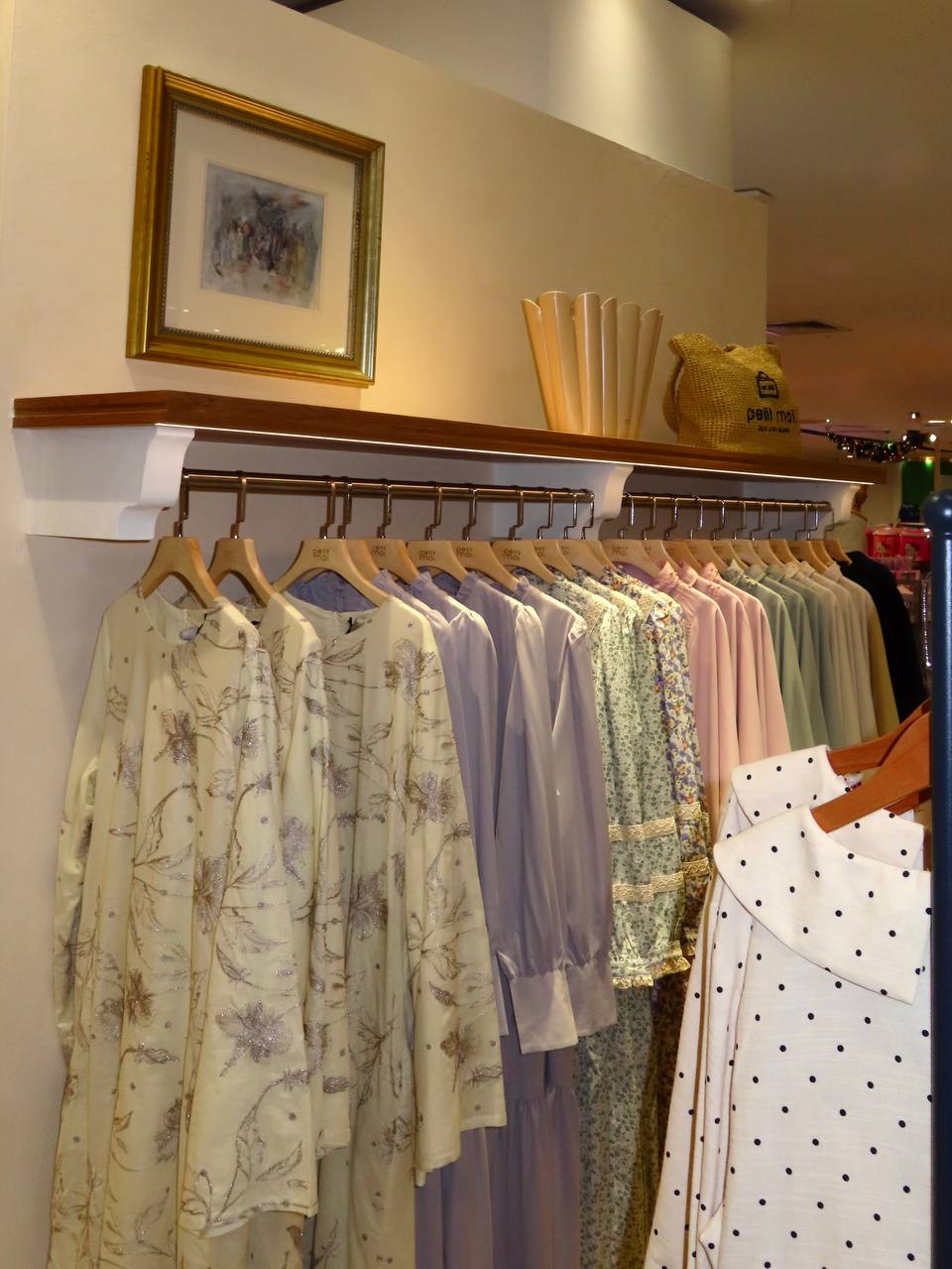 Petit Moi Isetan KLCC clothing display beneath timber shelving and framed artwork